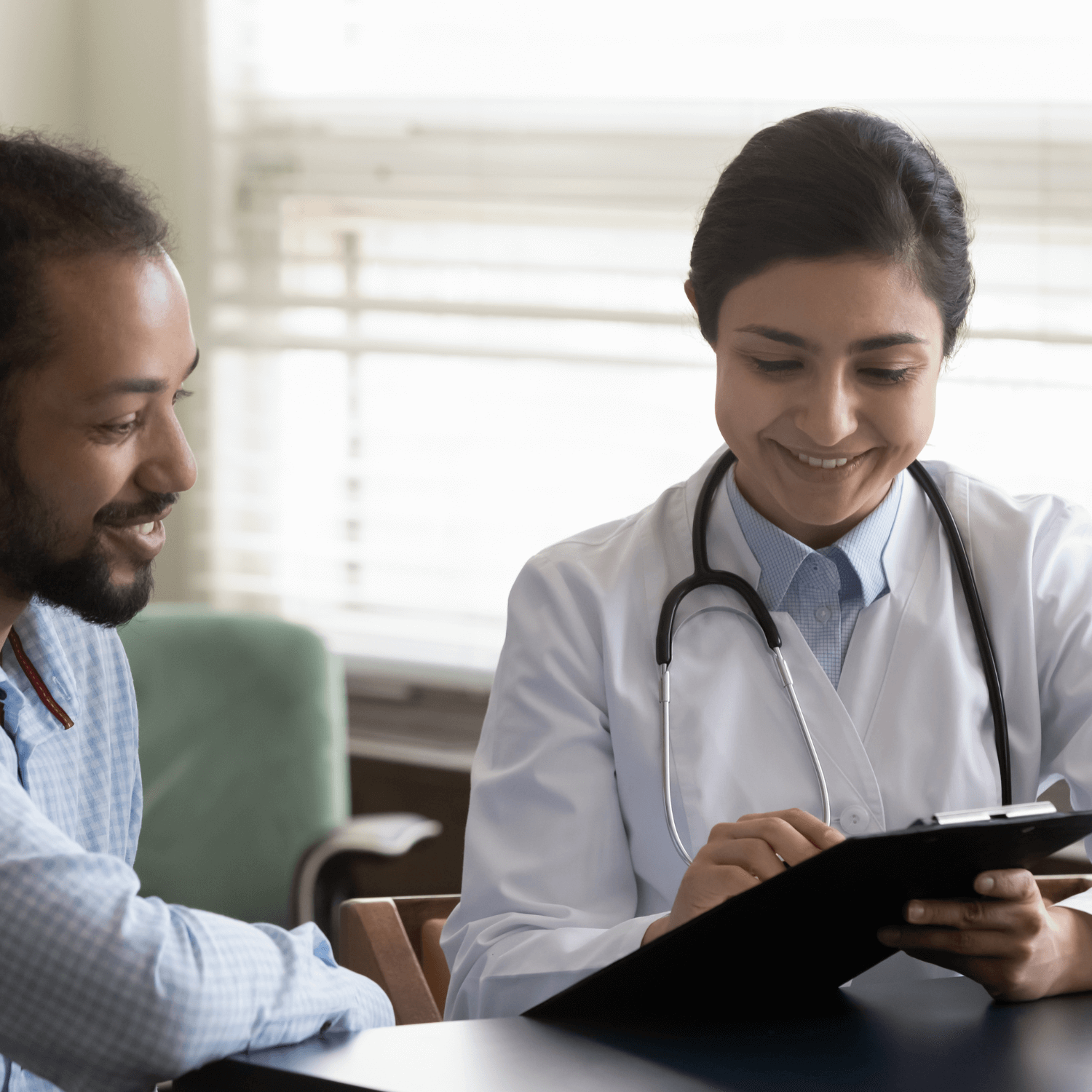 Image of female health care provider talking with a male patient, in front of a tablet.