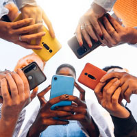 A group of people in a circle looking at their cell phones.