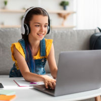 Girl wearing headphones using a laptop.